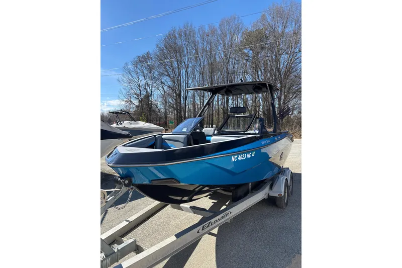 Slide: The Image of 2023 Axis T220 boat on trailer, blue exterior, parked outdoors. - 11