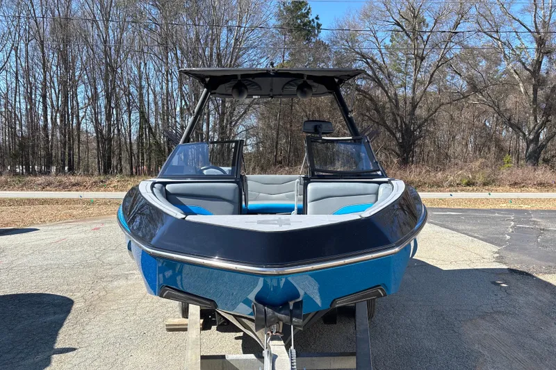 Slide: The Image of 2023 Axis T220 boat on trailer, parked outdoors, surrounded by trees. - 12