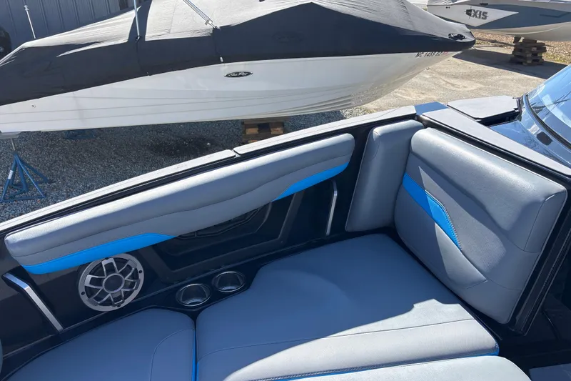 Slide: The Image of 2023 Axis T220 boat interior with blue and gray seating, speaker, and cup holders. - 14