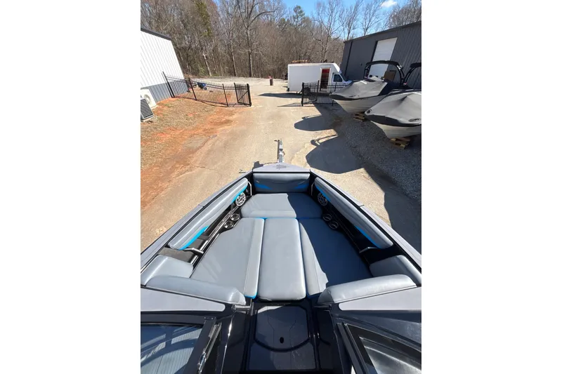 Slide: The Image of 2023 Axis T220 boat interior with gray seating, parked outdoors near other boats. - 16