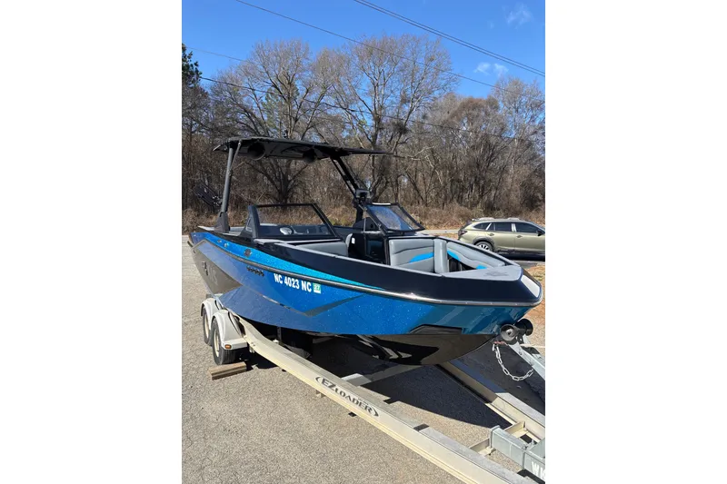 Slide: The Image of 2023 Axis T220 boat on trailer, blue exterior, parked outdoors. - 2