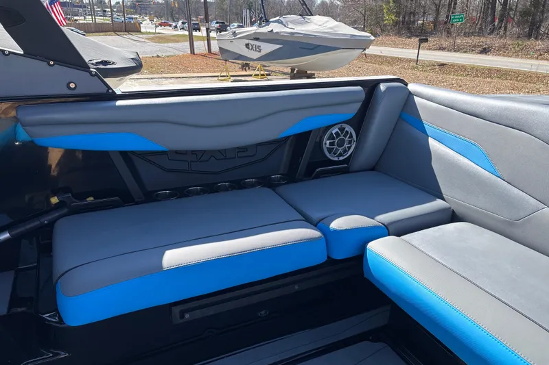Slide: The Image of 2023 Axis T220 boat interior with gray and blue seating, featuring a speaker and cup holders. - 23