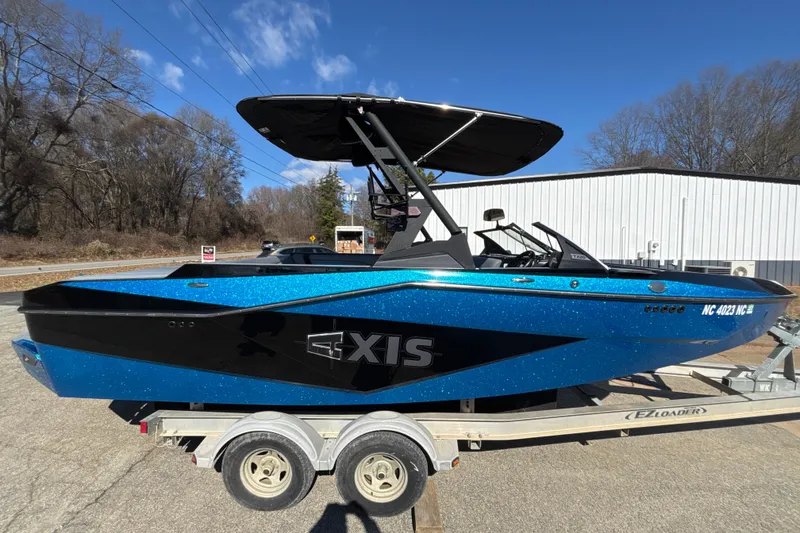 Slide: The Image of 2023 Axis T220 boat in blue and black on a trailer, parked outdoors. - 5