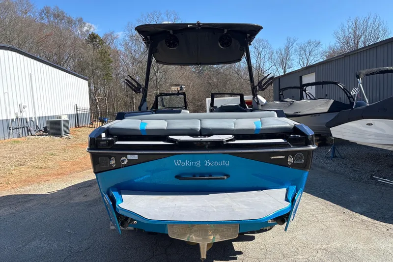 Slide: The Image of 2023 Axis T220 boat, blue, rear view, parked outdoors near buildings. - 7