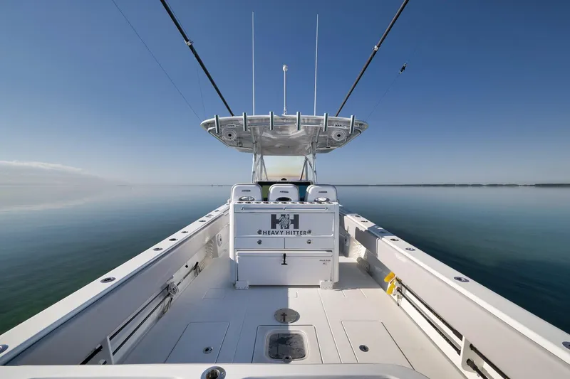 Slide: The Image of 2021 Contender 39 ST boat on calm water, clear sky, fishing rods visible. - 21