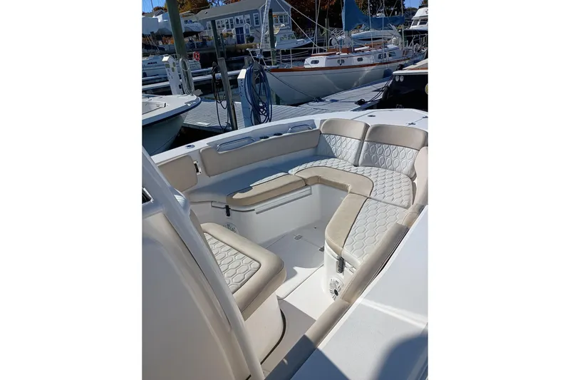 Slide: The Image of 2021 Sea Fox 228 Commander boat interior with beige cushioned seating at a marina. - 11