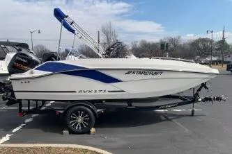 The Image of 2023 Starcraft SVX 171 OB boat on trailer, parked outdoors under a clear sky. - 1