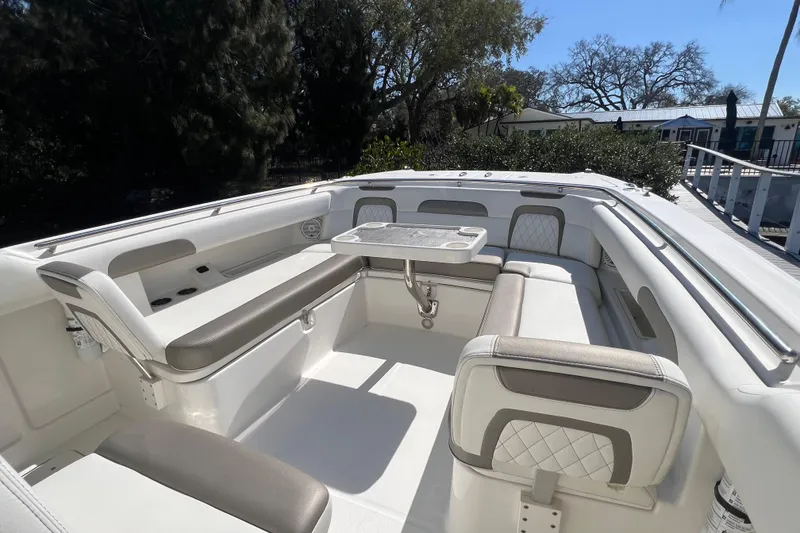 Slide: The Image of 2022 World Cat 280 CC-X boat interior with seating and table, surrounded by trees. - 34
