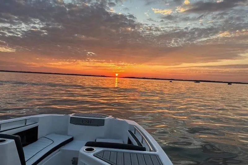 Slide: The Image of 2023 Yamaha Boats 255 FSH Sport E interior with helm and seating, at a boat dealership. - 23
