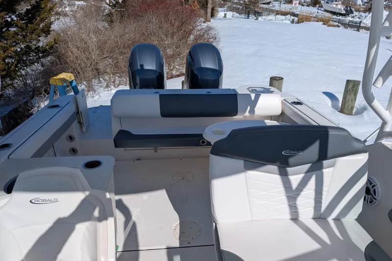 Slide: The Image of 2021 Robalo R247 Dual Console boat interior with seating and twin engines in snowy setting. - 15