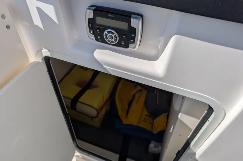 Slide: The Image of 2021 Robalo R247 Dual Console storage compartment with life jackets and Clarion audio system. - 16