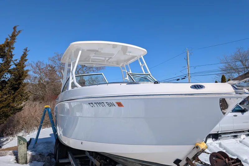 Slide: The Image of 2021 Robalo R247 Dual Console boat on trailer, snowy background, clear blue sky. - 2