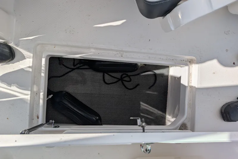 Slide: The Image of 2021 Robalo R247 Dual Console storage compartment with ropes and fenders. - 26