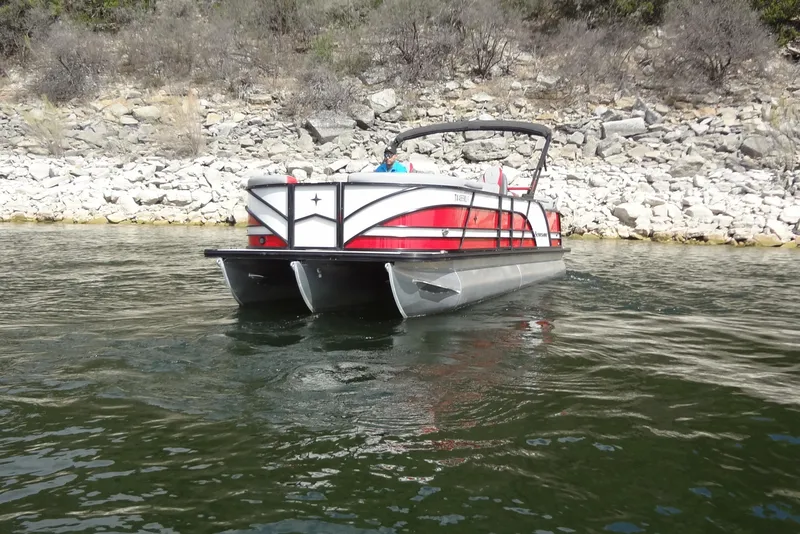 Slide: The Image of 2022 Berkshire 25RFX STS 3.0 pontoon boat on a rocky shoreline. - 2
