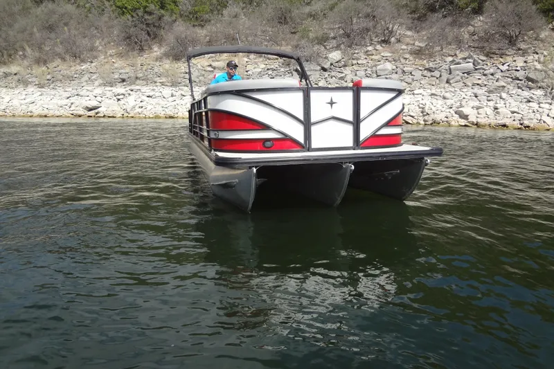 Slide: The Image of 2022 Berkshire 25RFX STS 3.0 pontoon boat on a calm lake near rocky shore. - 4