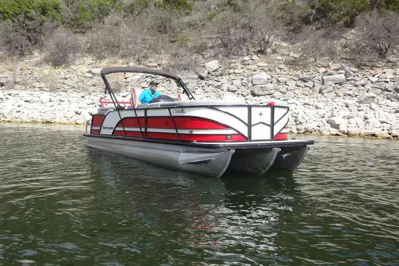 Slide: The Image of 2022 Berkshire 25RFX STS 3.0 pontoon boat on a calm lake near rocky shore. - 5