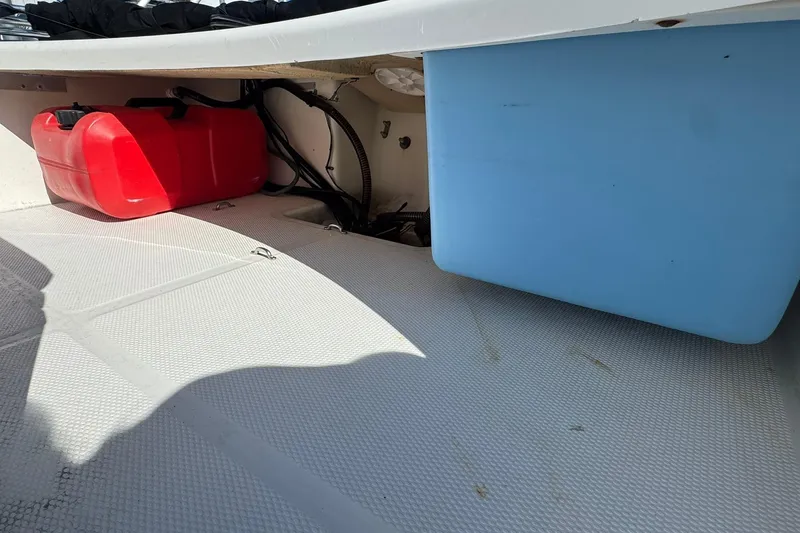 Slide: The Image of 2018 Mako Pro Skiff 17 CC storage area with red fuel tank and blue container. - 10