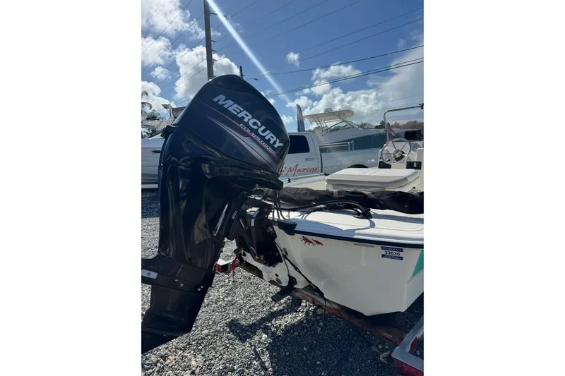 Slide: The Image of 2018 Mako Pro Skiff 17 CC with Mercury outboard motor, parked on gravel. - 6