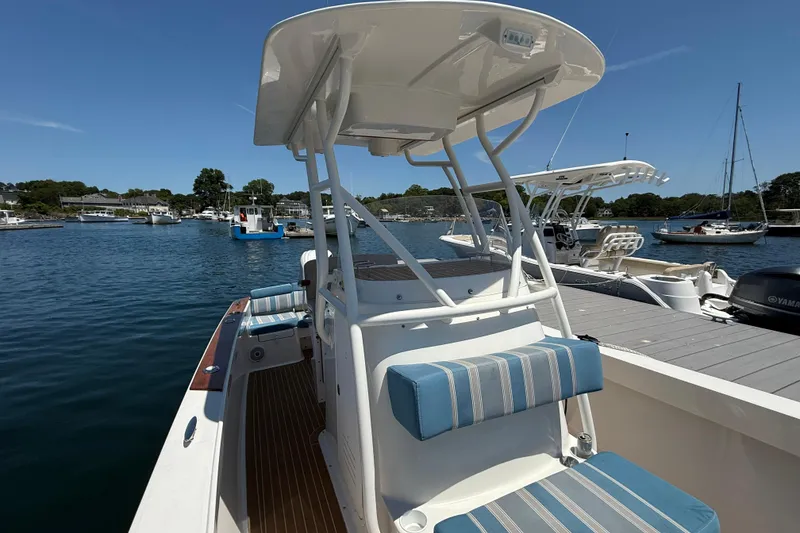 Slide: The Image of 2017 Vanquish Bristol Harbor 23 CC boat docked, featuring blue-striped seating and a T-top canopy. - 13
