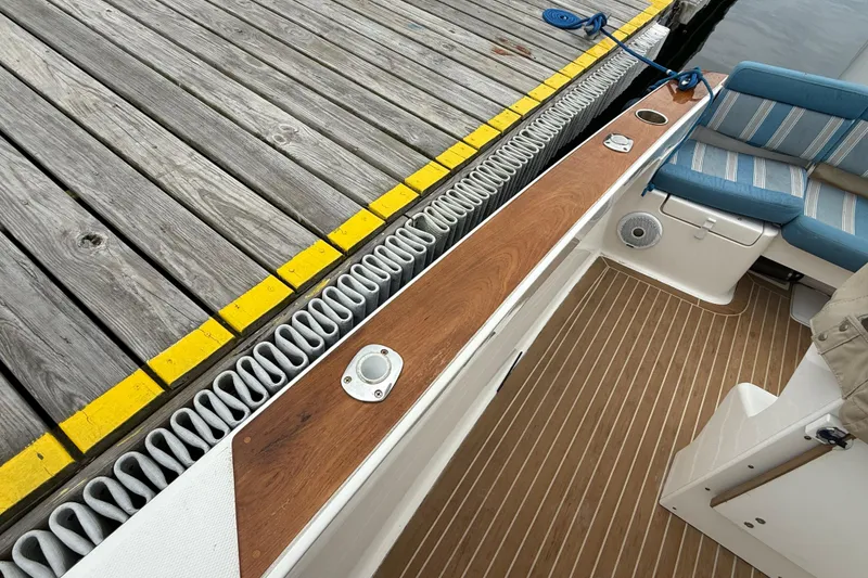 Slide: The Image of 2017 Vanquish Bristol Harbor 23 CC boat docked, featuring wooden deck and striped seating. - 19