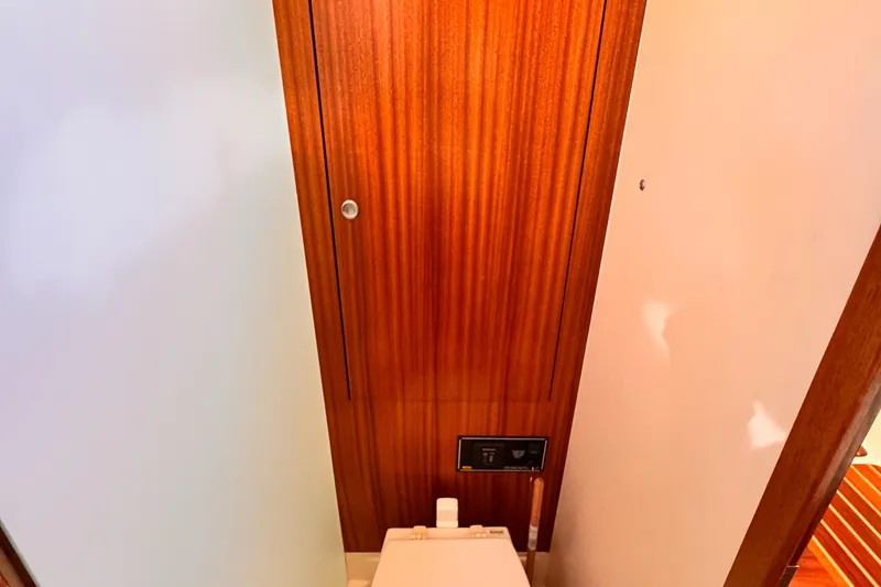 Slide: The Image of 2014 Pursuit OS 385 Offshore bathroom with wooden door and modern toilet. - 13