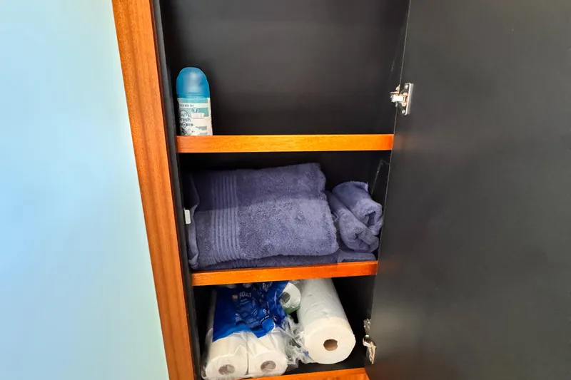 Slide: The Image of Cabinet with towels, paper towels, and spray on a 2014 Pursuit OS 385 Offshore. - 23