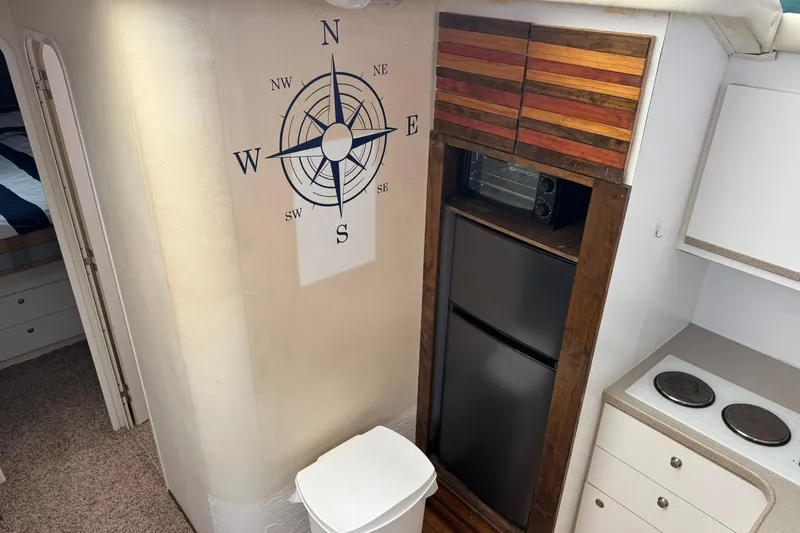Slide: The Image of Interior of 1996 Silverton 34 Motor Yacht with compass wall art and kitchenette. - 17