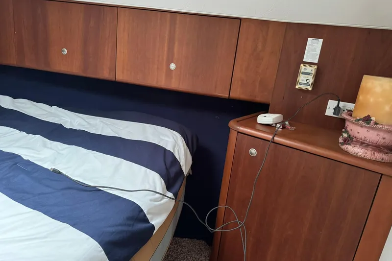 Slide: The Image of Interior cabin of 1996 Silverton 34 Motor Yacht with striped bedding and wooden cabinetry. - 19