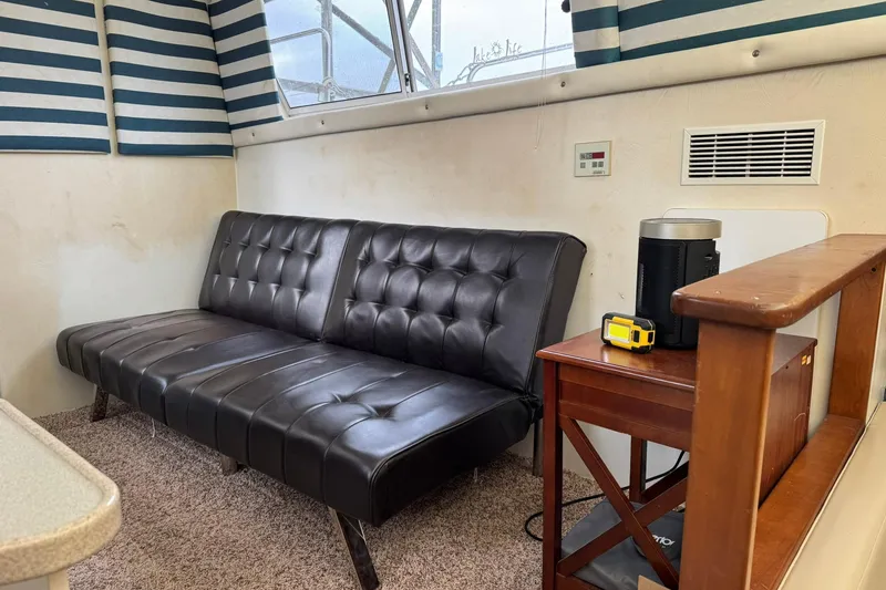 Slide: The Image of Interior of 1996 Silverton 34 Motor Yacht with black leather sofa and striped curtains. - 22