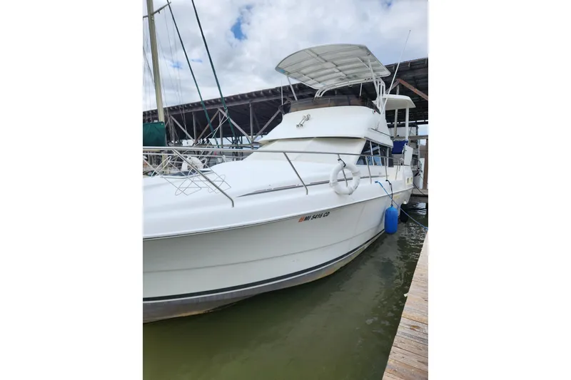 Slide: The Image of 1996 Silverton 34 Motor Yacht docked at marina, featuring white exterior and covered upper deck. - 7
