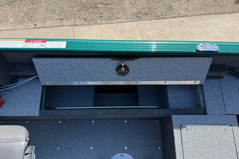 Slide: The Image of 2026 Lund 1650 Rebel XL SS boat interior with storage compartment and safety warnings. - 22