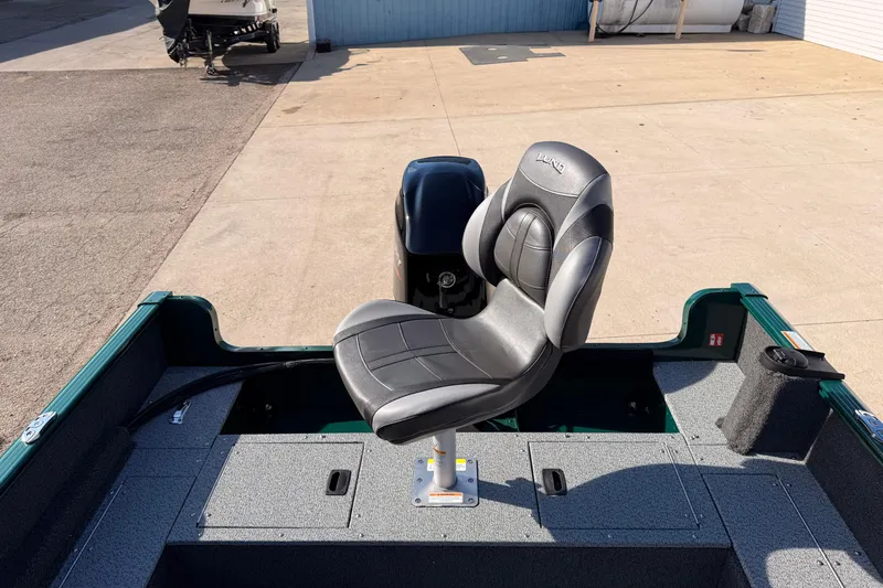 Slide: The Image of 2026 Lund 1650 Rebel XL SS boat with a swivel seat and motor, docked outdoors. - 23