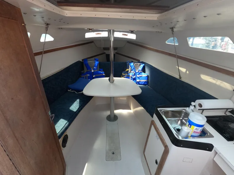 Slide: The Image of Interior of a 1998 Catalina 250 yacht with blue seating and small kitchenette. - 5