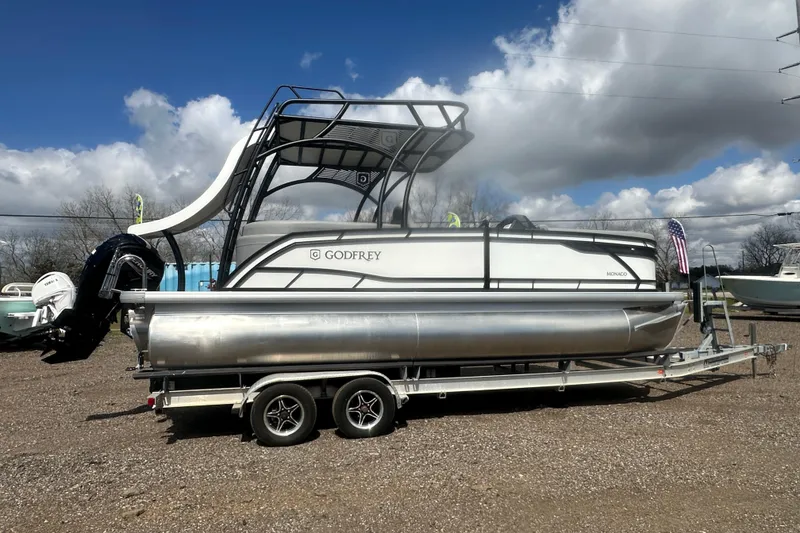 Slide: The Image of 2026 Godfrey Monaco Sun Deck 235 SDC pontoon boat on trailer under blue sky. - 10