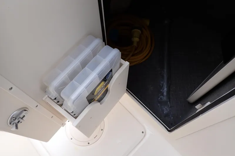 Slide: The Image of Storage compartment in 2016 Grady-White Freedom 275 boat with tackle boxes and coiled cable. - 53