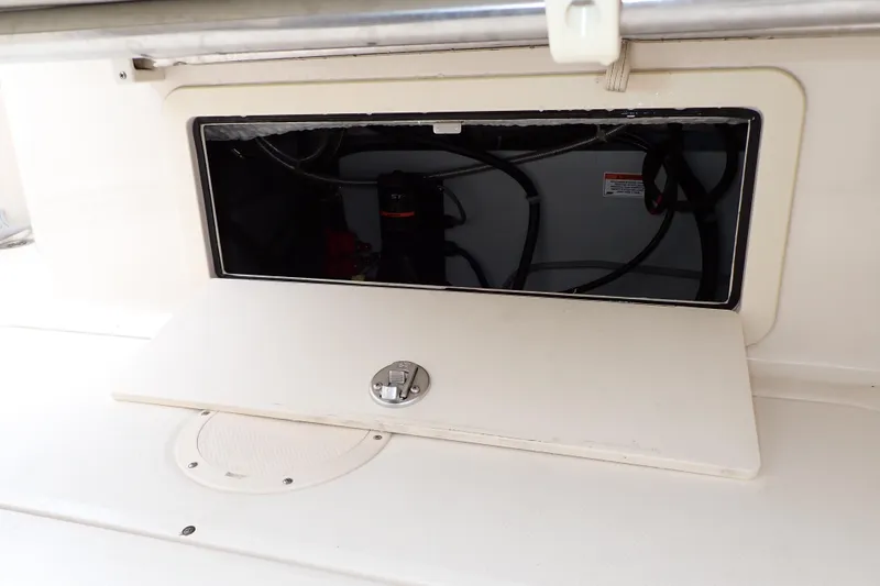 Slide: The Image of 2016 Grady-White Freedom 275 boat storage compartment with open hatch and visible wiring. - 77