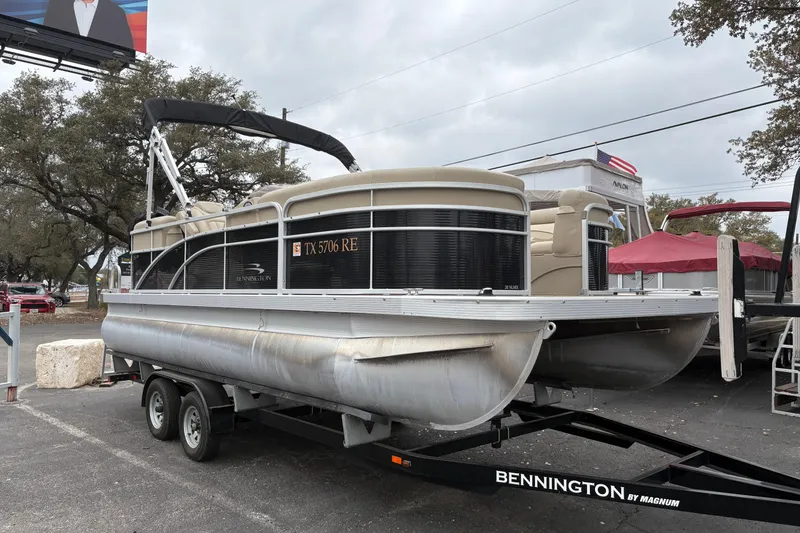 The Image of 2015 Bennington 20 SLMX pontoon boat on trailer, parked outdoors. - 1