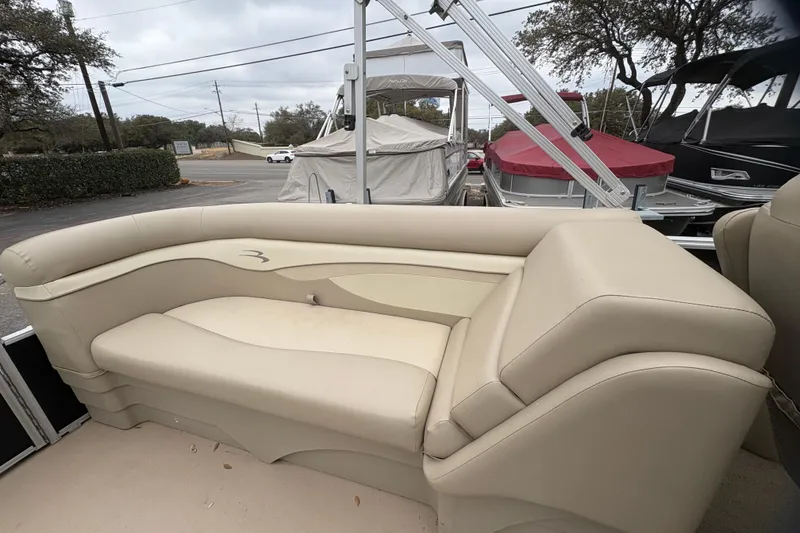 Slide: The Image of 2015 Bennington 20 SLMX boat interior with beige seating and outdoor setting. - 11