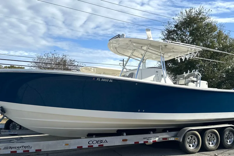 The Image of 2018 Regulator 34 Center Console boat on trailer, blue hull, clear sky background. - 1