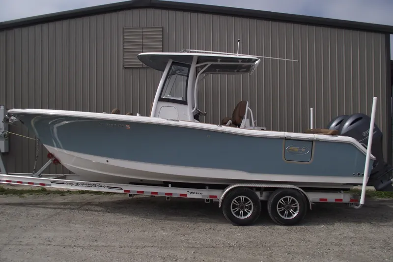 The Image of 2023 Sea Hunt Ultra 265 SE boat on trailer, parked by a metal building. - 0