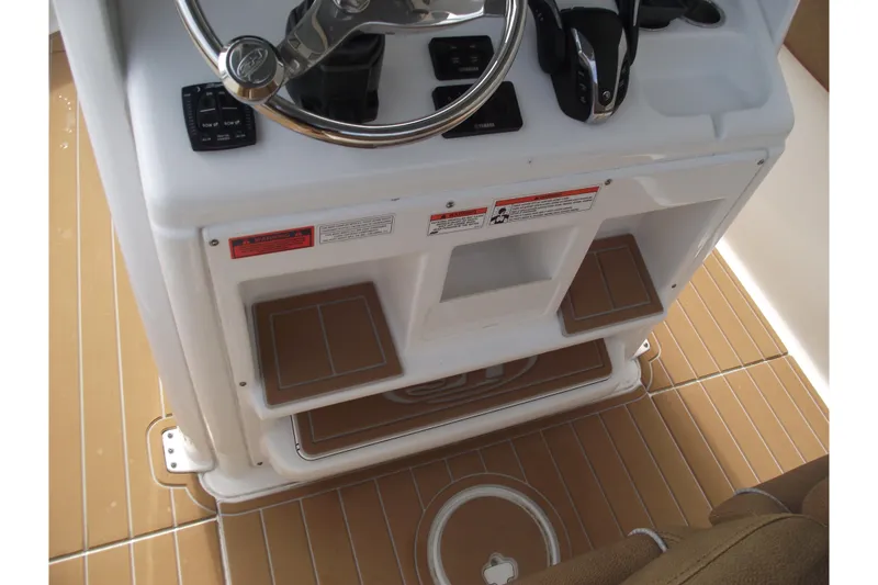 Slide: The Image of 2023 Sea Hunt Ultra 265 SE helm with steering wheel and controls on teak-style deck. - 28