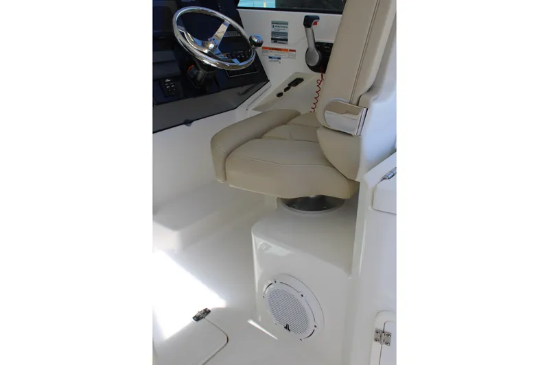 Slide: The Image of 2020 Pursuit DC 235 Dual Console boat interior with steering wheel and beige captain's seat. - 20