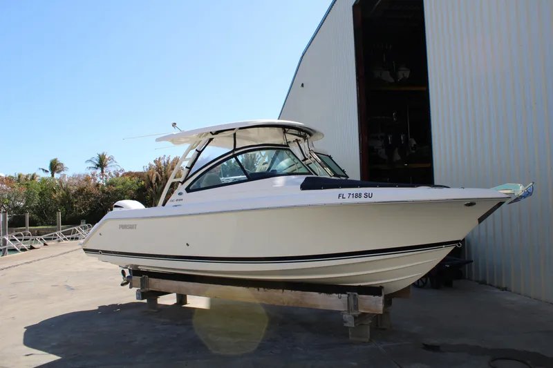 Slide: The Image of 2020 Pursuit DC 235 Dual Console boat on a stand near a warehouse. - 6