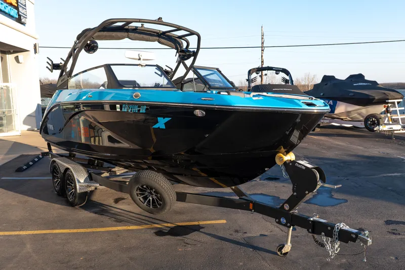 Slide: The Image of 2023 Yamaha Boats 222XD in black and blue on a trailer, parked outdoors. - 8