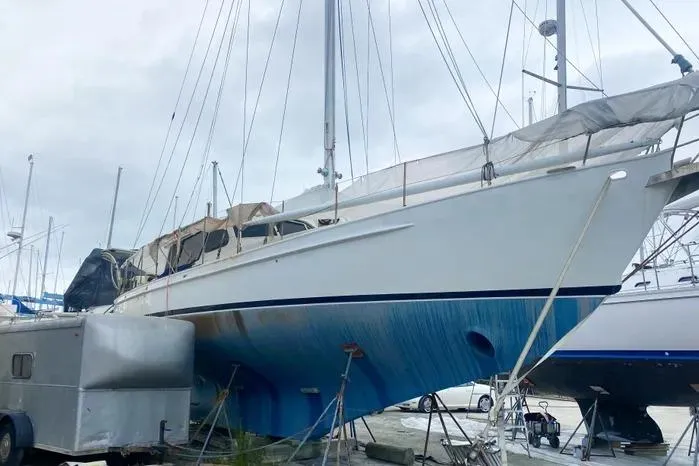 Slide: The Image of 1966 Vanguard Bermudian Sloop sailboat on land, with blue hull and covered deck. - 2