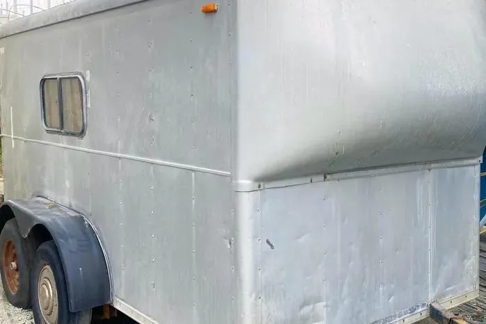 Slide: The Image of A weathered metal trailer with small window and rusted wheels. - 28