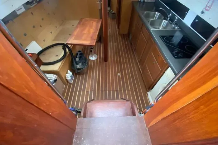 Slide: The Image of Interior of 1966 Vanguard Bermudian Sloop with wooden flooring and compact kitchen area. - 8