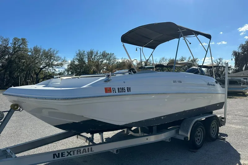 Slide: The Image of 2019 Hurricane SunDeck Sport 188 OB boat on trailer, parked outdoors under clear sky. - 3