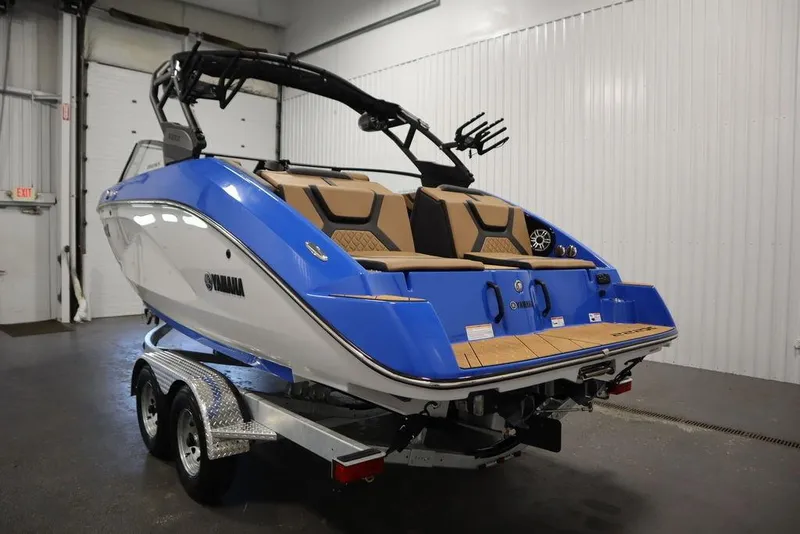 Slide: The Image of 2024 Yamaha Boats 222XE in showroom, blue and white exterior, on trailer. - 11