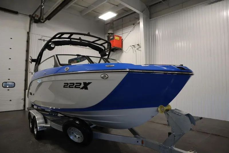 Slide: The Image of 2024 Yamaha Boats 222XE in a showroom, blue and white design on a trailer. - 3